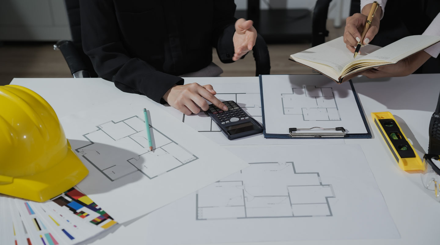Bureau avec plusieurs devis de travaux d'extension étalés, calculatrice et notes pour comparaison des offres d'artisans